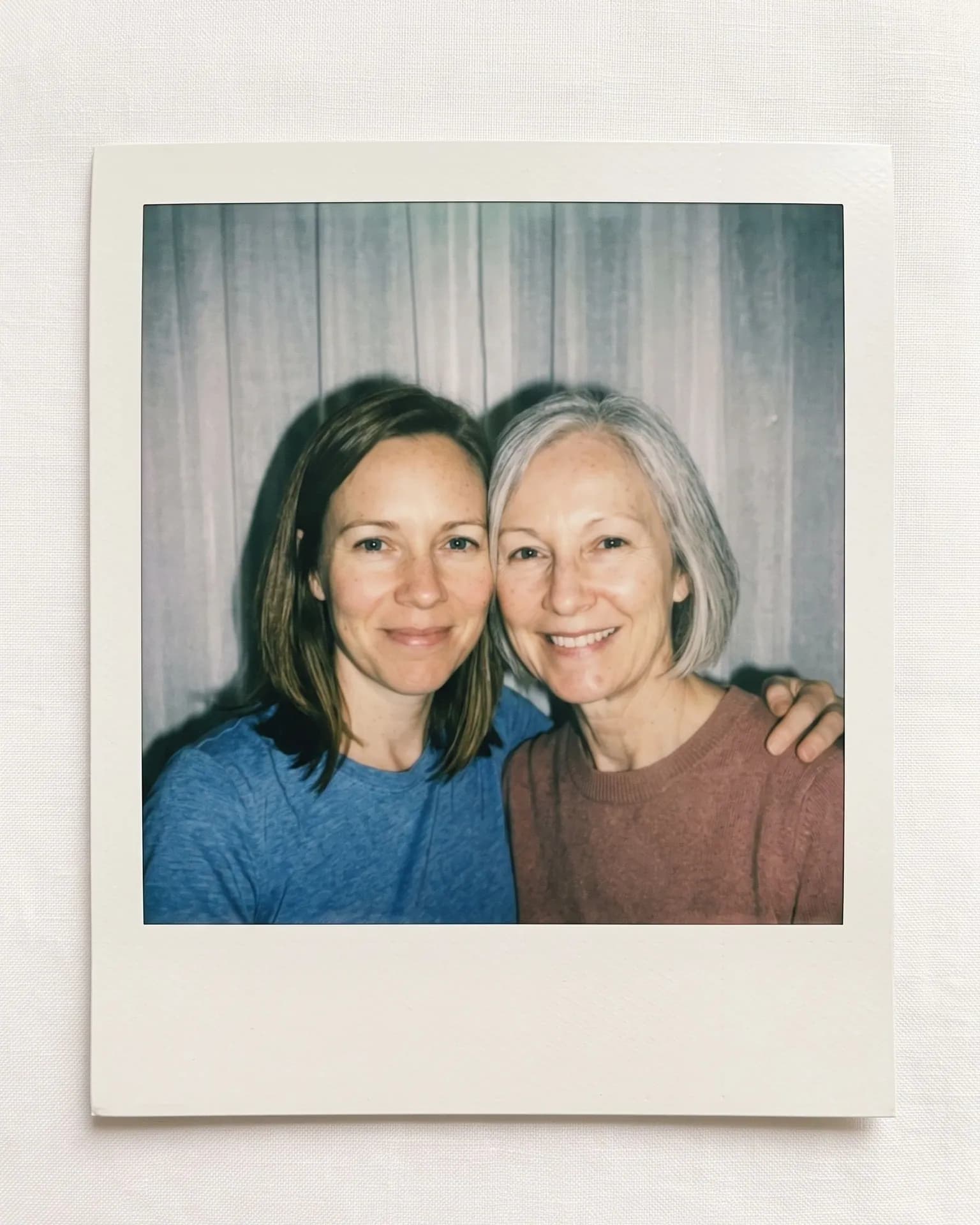 Instant print on linen: a younger woman and an older woman with a silver bob cheek to cheek in flash light