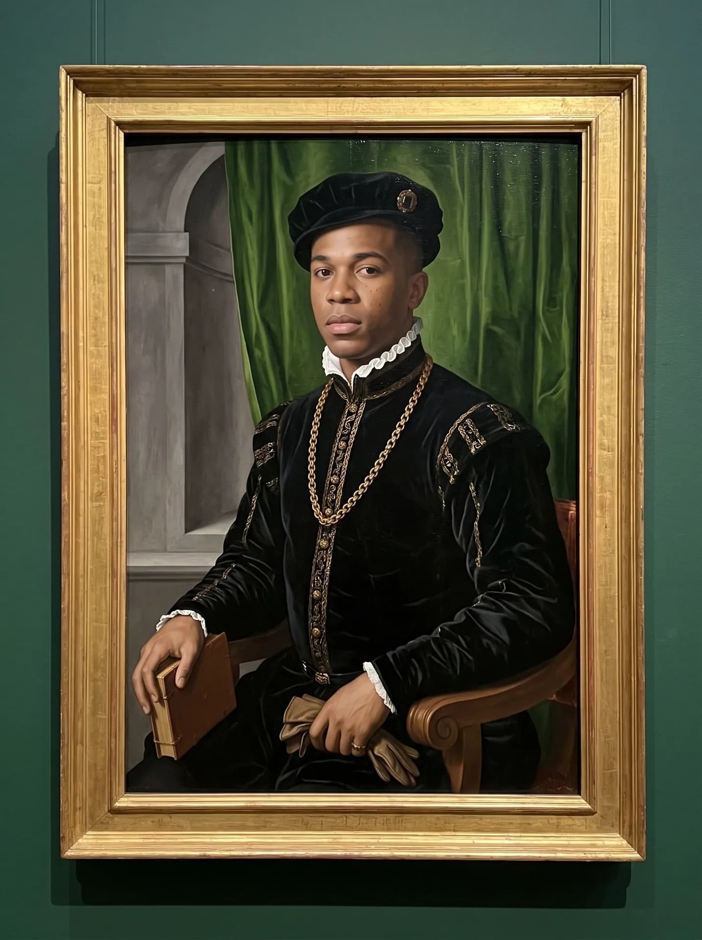 Renaissance oil portrait of a man with dark brown skin in a black velvet doublet, ruff, gold chain and cap, in a gilded frame