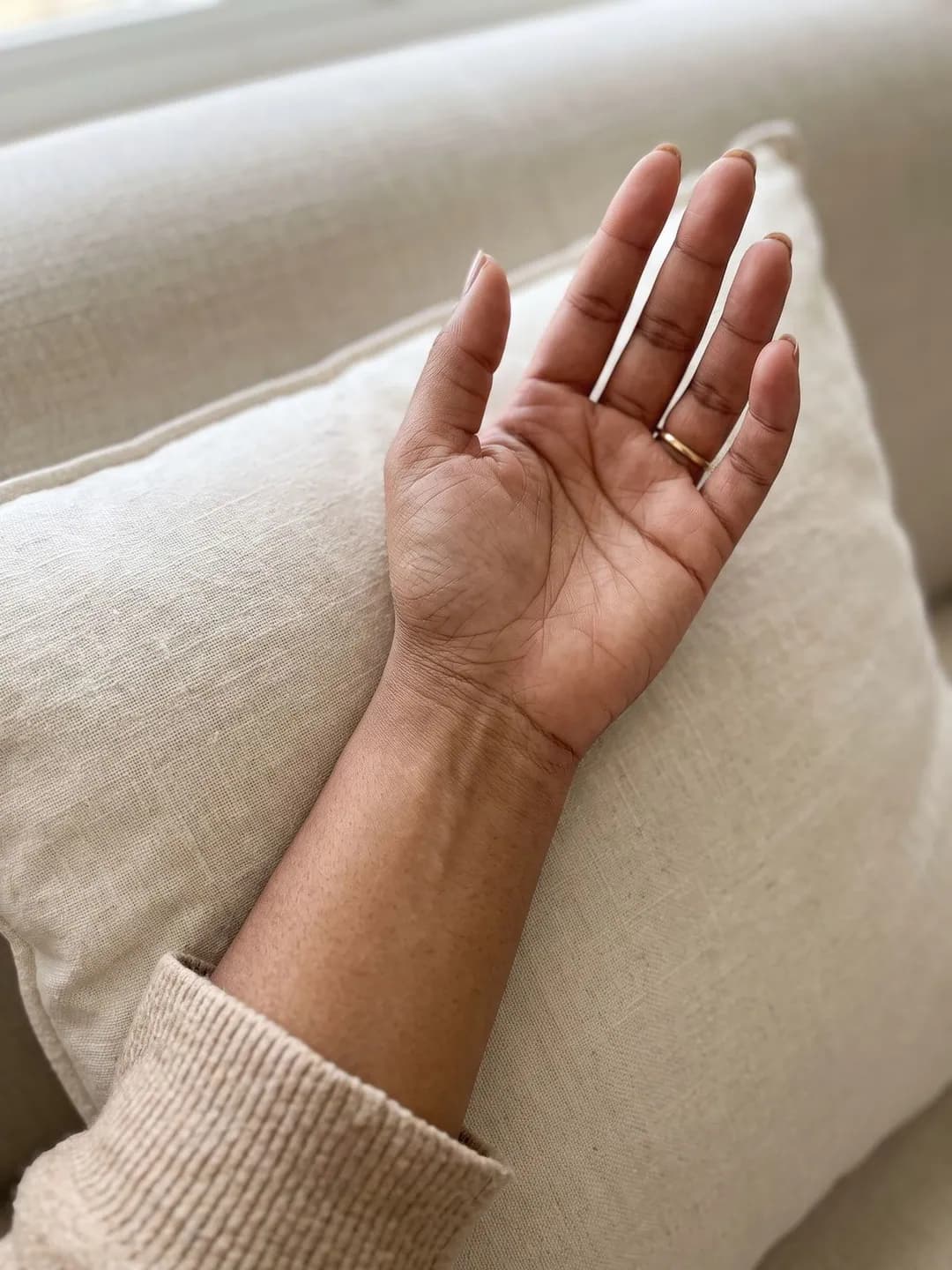 AI-generated sample input: a woman's inner wrist with warm medium-brown skin and a thin gold ring, palm up on a linen cushion