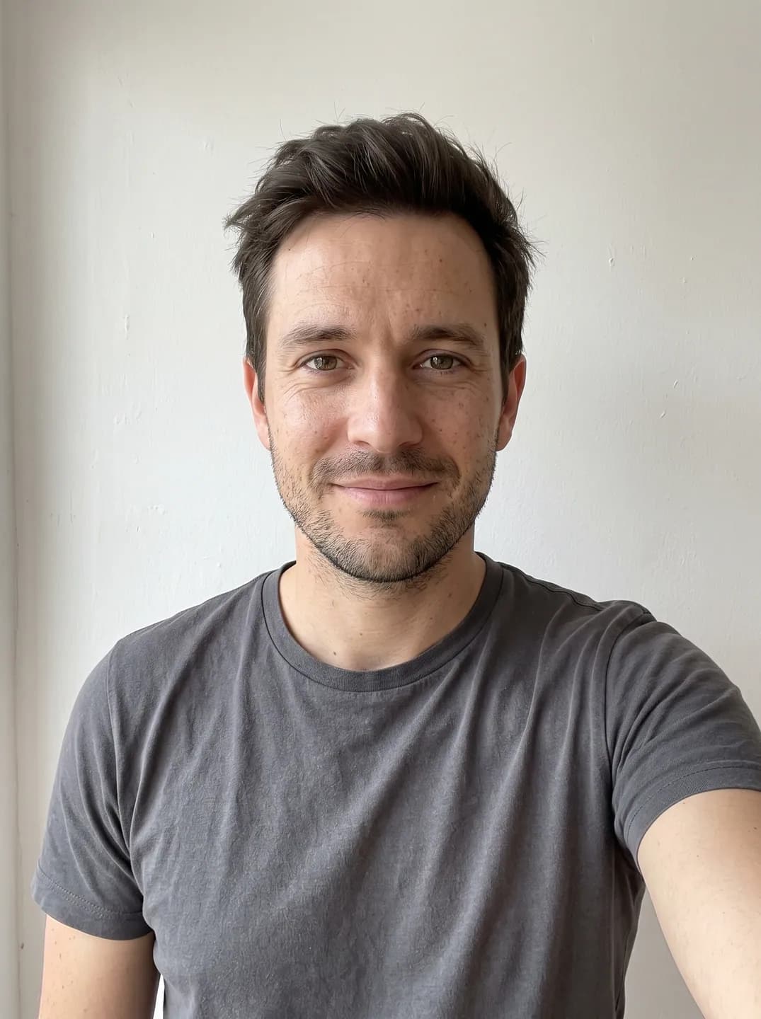 AI-generated sample input: front-facing selfie of a man with short dark brown hair and stubble in a gray T-shirt