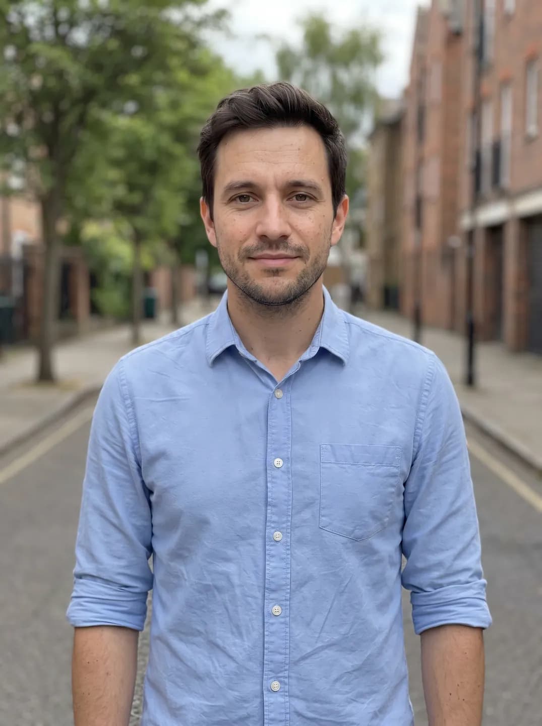 AI-generated sample input: waist-up photo of a man with short dark hair and stubble in a light blue shirt on a street