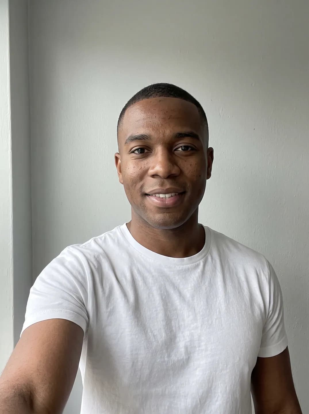 AI-generated sample input: front-facing selfie of a man with dark brown skin and a short fade haircut in a white T-shirt