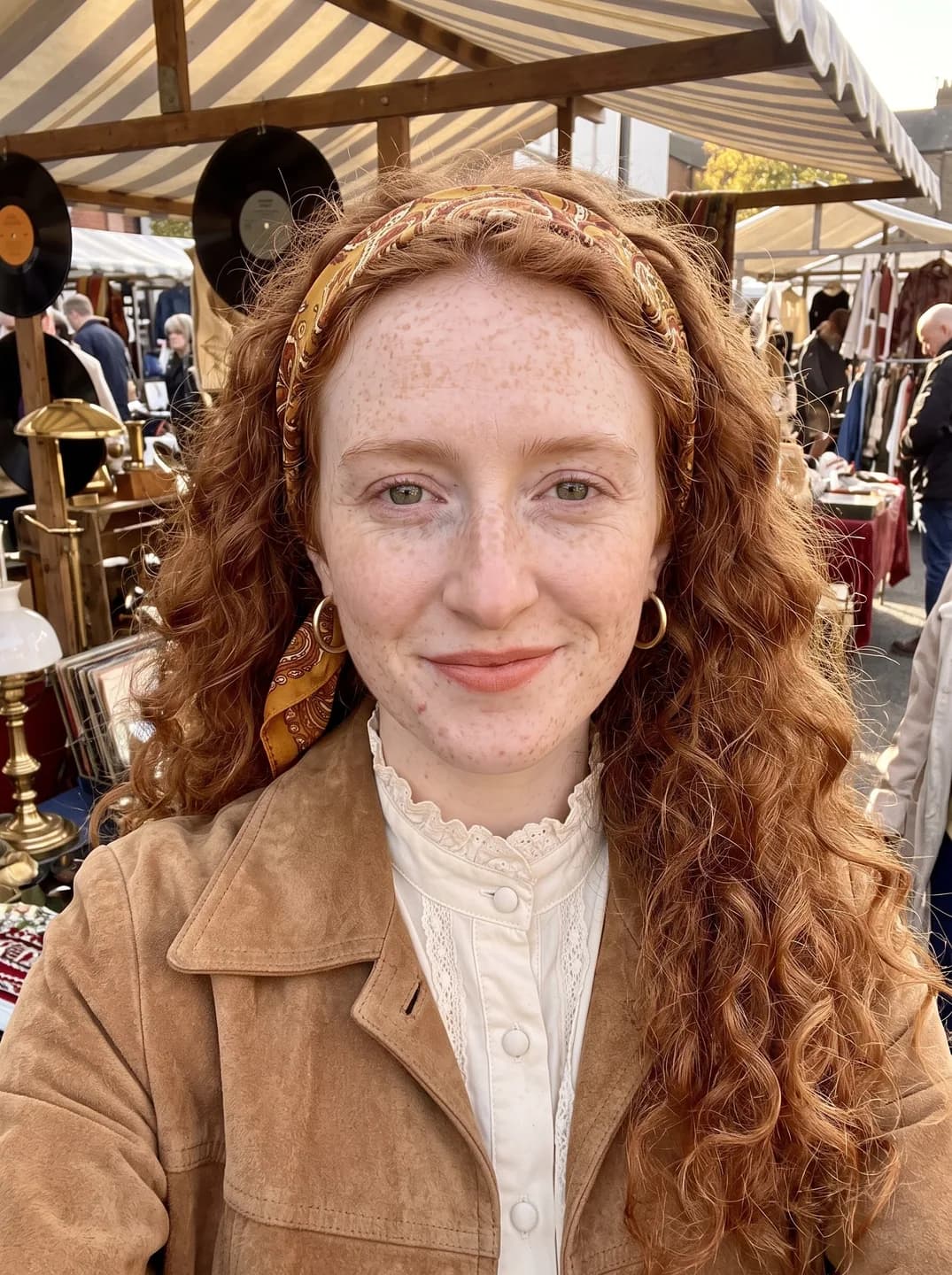 AI-generated sample input: front-facing selfie of a woman with long curly copper-red hair, dense freckles and a paisley headscarf in a tan suede jacket at a flea market