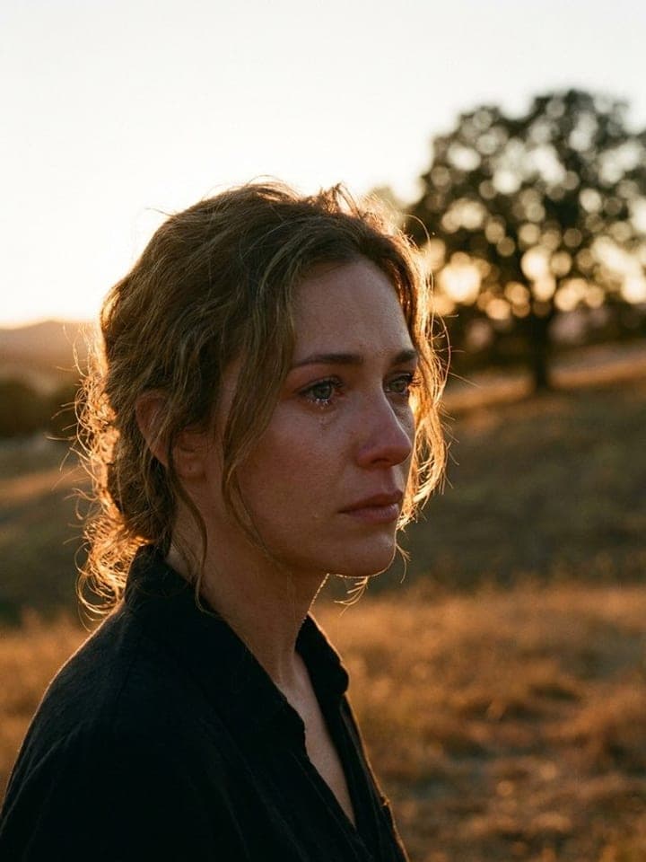 Woman with loose curly hair in warm sunset backlight in a golden field, soft bokeh behind
