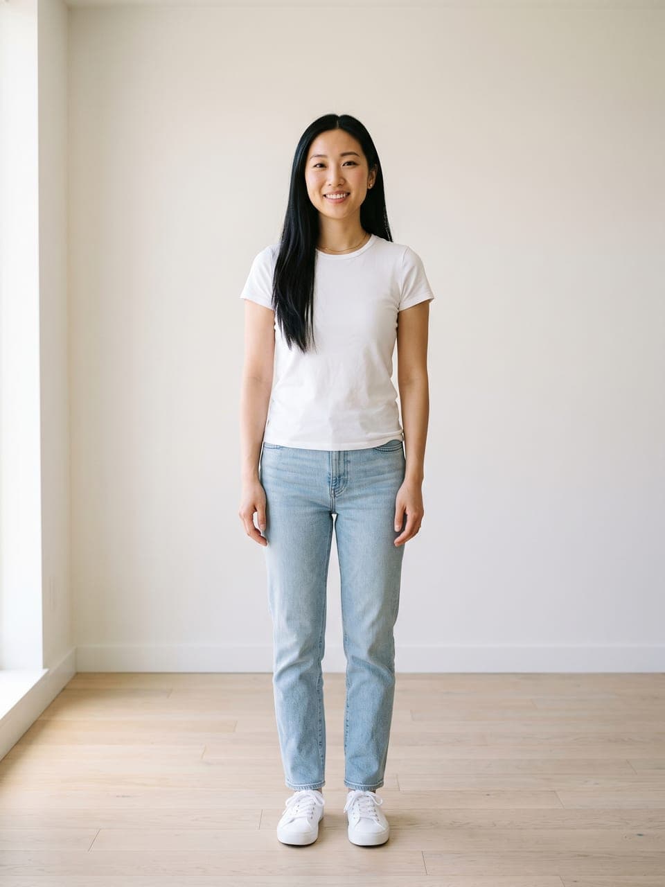 Ganzkörperfoto einer Frau in weißem T-Shirt und heller Jeans in einem hellen Raum