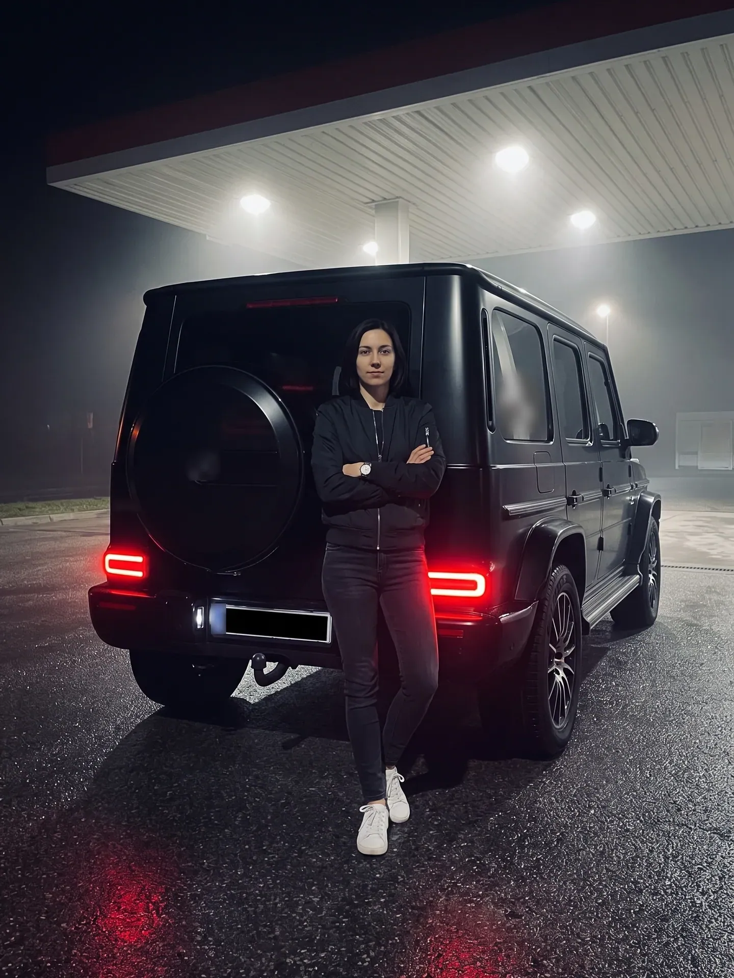 Woman in a black bomber leaning on a black G-Class at a foggy night gas station, made with the Photo with a G-Wagon template